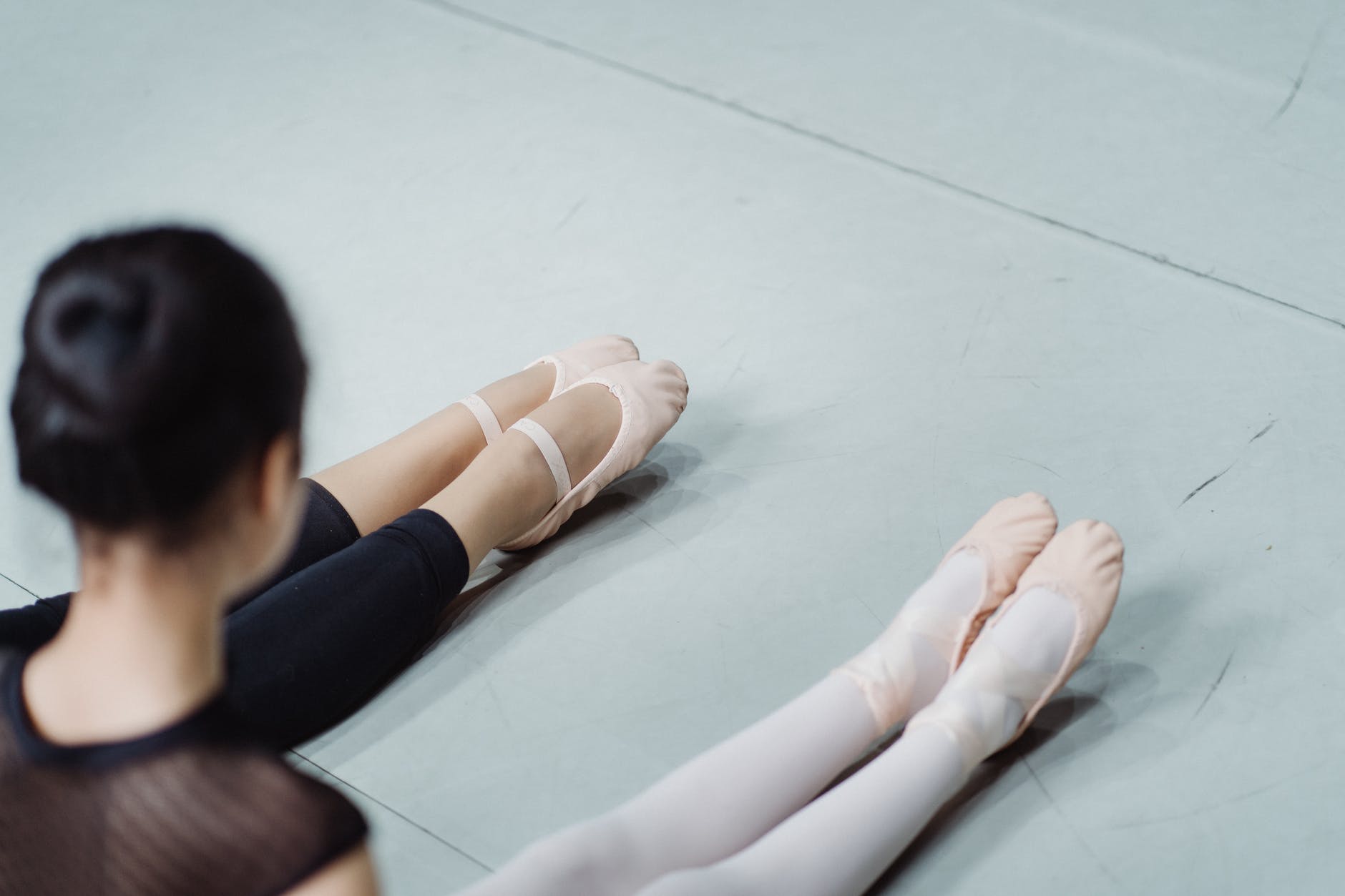 faceless trainer teaching girl while performing ballet exercise